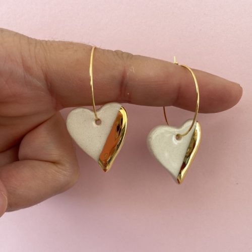 Pendientes de aro con colgante de cerámica en forma de corazón blanco y dorado.